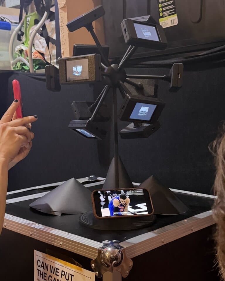 The assembled video sphere standing on a road case, screens playing live content, with a phone at its base showing a basketball game