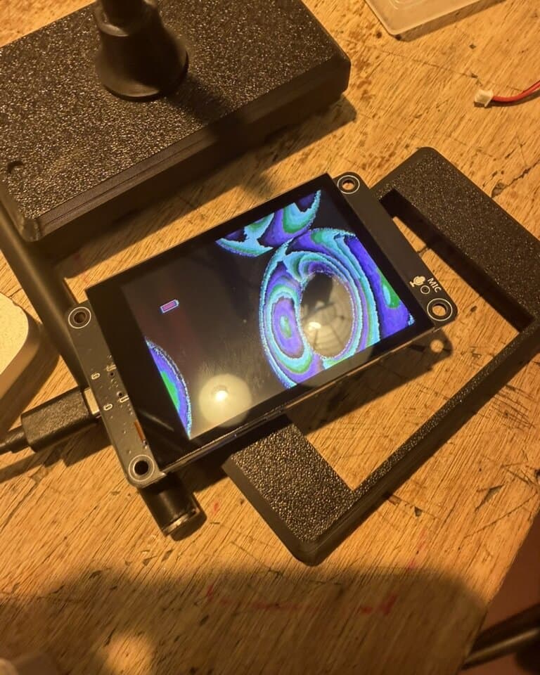 A screen module mid-assembly on the bench, rendering a swirling blue and purple pattern