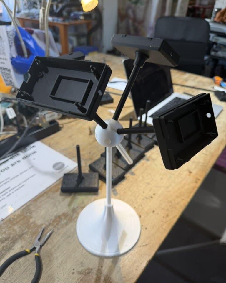 The first full-form prototype on the bench: pedestal, long stem, hub, and three empty case backs on stems, no electronics yet