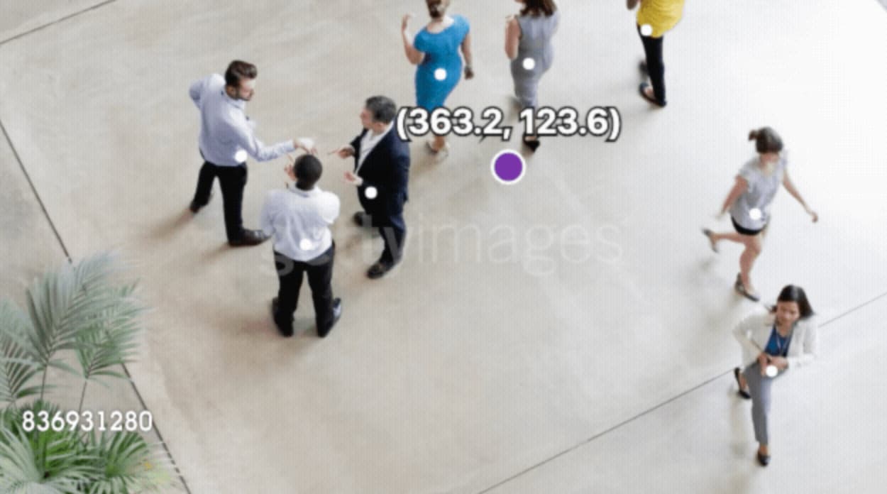 Top down view of individuals in a lobby. A purple blob is in the center of the photo and smaller white circles are on each individual.